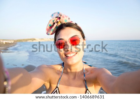 Beautiful smiling woman is taking selfie on the beach.
