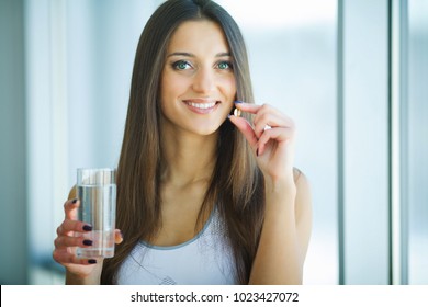 Beautiful Smiling Woman Taking Vitamin Pill. Dietary Supplement