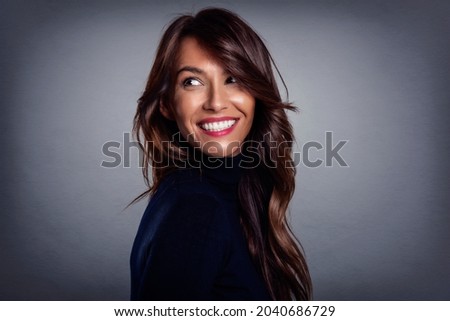 Beautiful smiling woman with white teeth standing at isolated grey background. Happy woman wearing turtleneck sweater. Copy space. 

