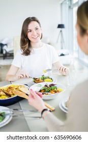 Beautiful Smiling Women Eating Together At The Table In Modern Apartment