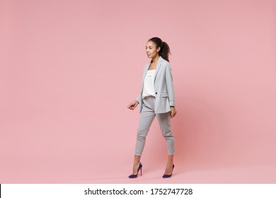 Beautiful Smiling Young African American Business Woman In Grey Suit, White Shirt Posing Isolated On Pink Background. Achievement Career Wealth Business Concept. Mock Up Copy Space. Looking Aside