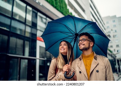 beautiful smiling young couple walking in the rain - Powered by Shutterstock