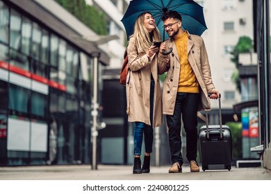 beautiful smiling young couple walking in the rain - Shutterstock ID 2240801225