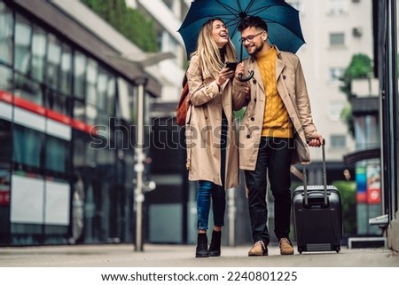 beautiful smiling young couple walking in the rain