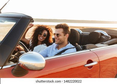 Beautiful smiling young multiethnic couple riding in a convertible
