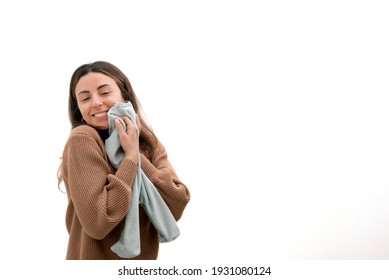 Beautiful Smiling Young Pregnant Woman Is Holding A Onesie, Tight To Her Chest, With Love