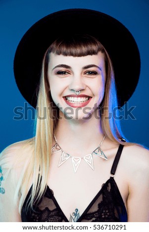 beautiful smiling young woman in black hat posing in studio