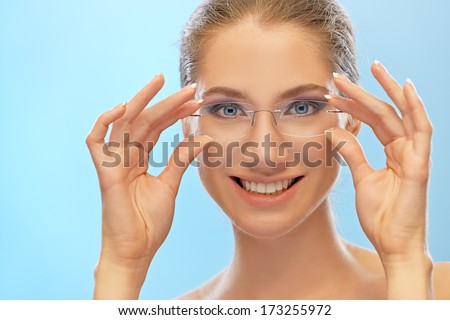 Beautiful smiling young woman holds her hands glasses, on blue background.