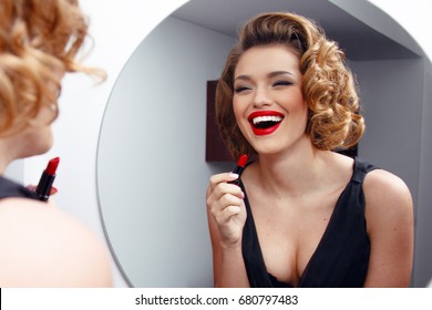 Beautiful Smiling Young Woman With Perfect Make Up, Red Lips, Retro Hairstyle In Black Dress, Looking In Mirror. Horizontal View.