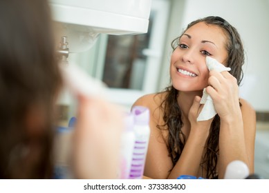 Beautiful Smiling Young Woman Removing Make Up With A Facial Wipe In Front Of Mirror.