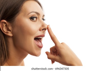 Beautiful smiling young woman touching her nose on white background