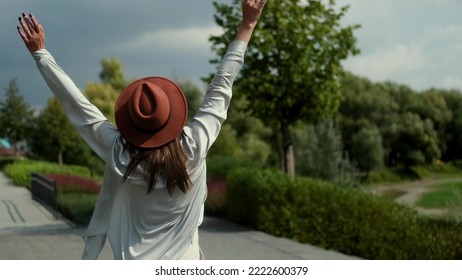 A beautiful smiling young woman walks in a summer park, and spins happily, posing for the camera. Portrait of a woman breathing fresh air, relaxed, feeling alive, releasing from work or relationships