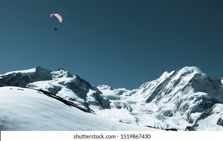 Beautiful snow-capped mountain view with paraglider. Paragliding in Swiss alps Matterhorn region, Switzerland. Concept of extreme sport, taking adventure/ challenge. 