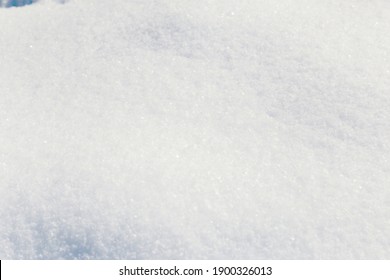 A beautiful snowy surface of fluffy snow under the bright winter sun, with shadows and snowflakes.