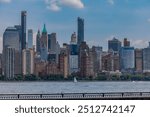 Beautiful soft image of the New York City Skyline taken from across the Hudson River in Jersey it’s, New Jersey with sailboats, One World Trade Center, the Empire State Building and historic others