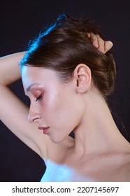 A Beautiful, Sophisticated Woman With Beautiful Makeup Stands On A Dark Background Collecting Her Hair With Her Hands