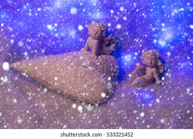 beautiful soulful figurine composition of cupid angels for valentine day or christmas with small pillow in shape of heart lying on white wadding decorating snow under snowflakes - Powered by Shutterstock