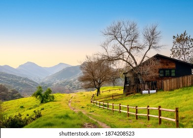 Beautiful Southern California Rural Landscape, With Fenced Wooden Hut On A Green Meadow And Hazy Mountains Background.