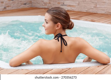 Beautiful spa. Back view of a young woman enjoying Jacuzzi in a spa center - Powered by Shutterstock