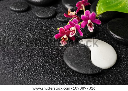 Beautiful spa concept of zen and sign Yin-Yang stones with drops, red orchid (phalaenopsis) and green leaf. Copy space
