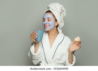 Beautiful Spa Woman In Cosmetic Face Mask Eating Breakfast And Drinking Coffee On Gray Background