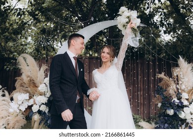 Beautiful Space Wedding Ceremony In The Summer Of A Chic Couple, The Groom In A Suit And The Bride In A White Luxurious Wedding Dress.