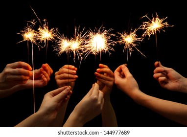 beautiful sparklers in hands on black background 