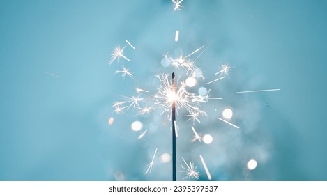 Beautiful sparkles from sparklers on the background of New Year's bokeh, Christmas mood, glitter, festive background. Bright fire on a blue background. - Powered by Shutterstock