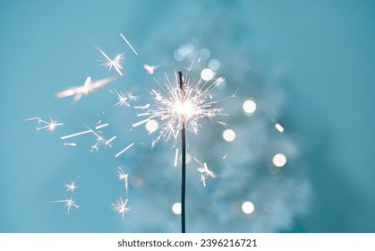 Beautiful sparkles from sparklers on the background of New Year's bokeh, Christmas mood, glitter, festive background. Bright fire on a blue background. - Powered by Shutterstock