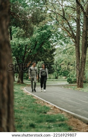 Beautiful sport couple walking and talking on the path in the park