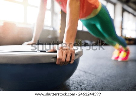 Beautiful sport woman exercising on balance ball in gym, performing pushups. Routine workout for woman's physical and mental health.