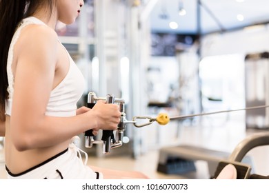 Beautiful sport woman is pulling and holding the handle of machine for exercise her back. Charming beautiful girl wears sexy white sportswear. Pretty young lady look strong, copy space, gym background - Shutterstock ID 1016070073