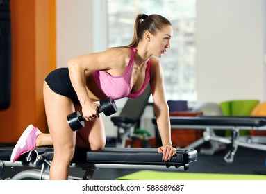 Beautiful sportive woman training with dumbbell in gym - Shutterstock ID 588689687