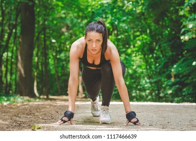 Beautiful sportswoman in starting position ready for morning workout in nature. - Powered by Shutterstock