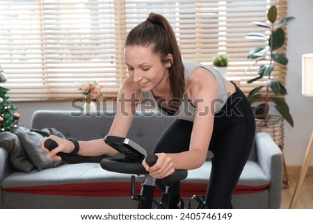 Beautiful sportswoman working out on on a smart exercise bike at home..