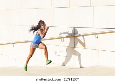 Beautiful sporty african woman rooning on stairs in the street, health lifestyle concept. - Powered by Shutterstock