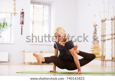 Beautiful sporty fit yogi woman practices yoga asana Eka Hasta Bhujasana pose in the fitness room
