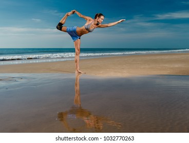 Beautiful sporty fit yogini woman practices yoga asana Virabhadrasana - warrior pose , on the beach 