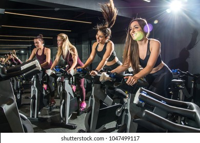 Beautiful sporty girls riding exercise bikes in gym. - Powered by Shutterstock