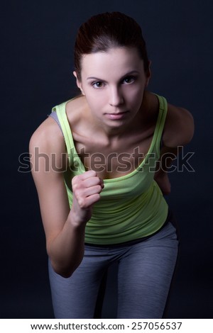 Similar – Close up front portrait of one young athletic woman in sportswear in gym over dark background, standing in boxing stance with hands and fists, looking at camera