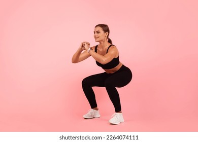 Beautiful Sporty Young Woman Doing Deep Squat Exercise Over Pink Background In Studio, Motivated Millennial Female Making Fitness Training Indoors, Enjoying Healthy Lifestyle, Copy Space - Powered by Shutterstock