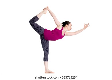 Beautiful sporty young woman doing Natarajasana, Dancer king pose (Dandayamana-Dhanurasana, Standing Bow Bikram posture), studio full length isolated shot on white background, side view