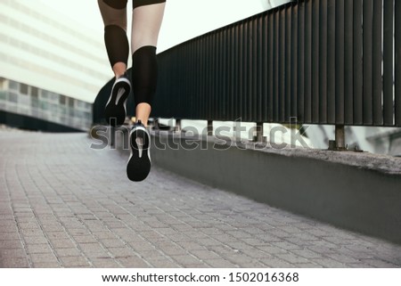 Beautiful sporty young woman running on street, closeup
