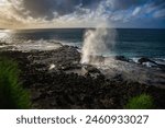 THE BEAUTIFUL SPOUTING HORN SPRATING WATER INTHE AIR WITH A BEAUTIFUL SKY AND SUNSET WITH A REFLECTION OFF OFTHE ROCKS ON KAUAI HAWAII