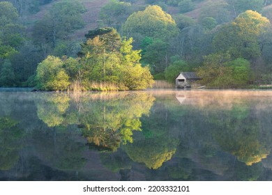 Beautiful Spring Colours On Trees At Rydal Water In The Lake District, UK. Perfect Reflections In Misty Water With Small Boathouse. UK Landscape Photography.