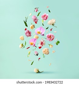 Beautiful spring flowers flying in the air, against teal background; Creative spring floral layout. Minimal birthday, valentines or wedding concept. - Shutterstock ID 1983432722