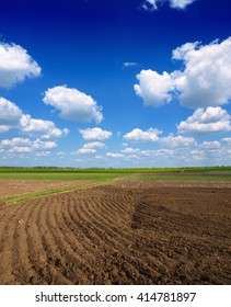 Beautiful spring landscape with plowed field under blue sky with clouds