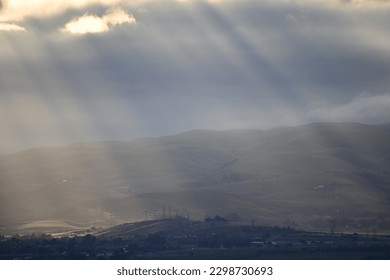beautiful spring time view of sun shining through slits in the clouds on a stormy day