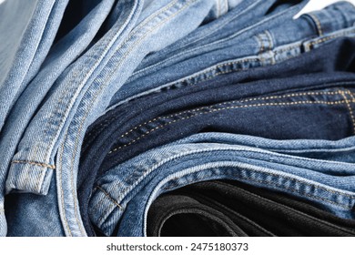 A beautiful stack of folded denim jeans in different shades of blue and black. Denim background - Powered by Shutterstock