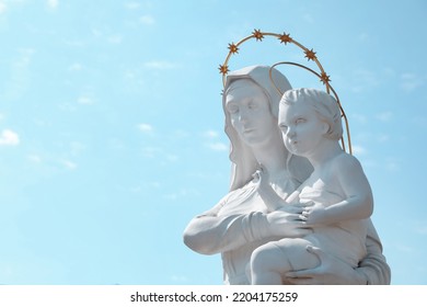 Beautiful Statue Of Virgin Mary And Baby Jesus Against Blue Sky. Space For Text